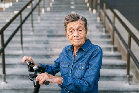 90 year old woman with grey hair, wrinkles, progressive and active uses modern electric transport