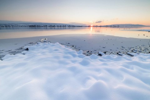 Winter landscape with a frozen lake at sunset, soft snow cover and reflecting water, Seegarten,