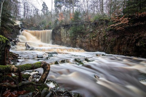 Landscape shot of a large waterfall in a spruce and birch forest and in nature. Autumn landscape
