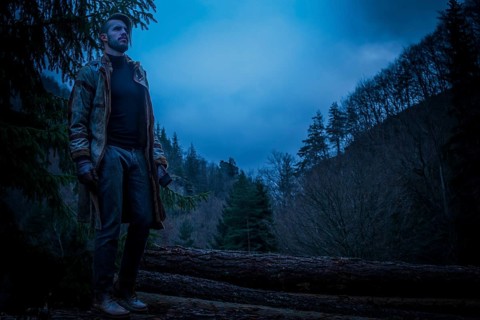 Young man in the forest at night. Early morning