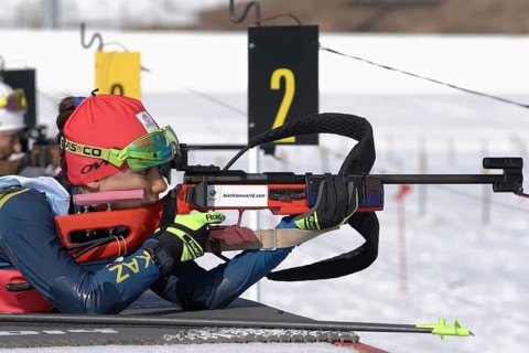 Sportswoman biathlete aiming, rifle shooting, reloading prone position. Biathlete Polina Yegorova