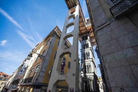An urban area with historic buildings and an iconic lift under a blue sky in Lisbon, Elevador de