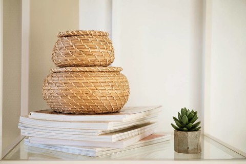 Close-up of a round straw box with a lid on a white shelf. Eco-friendly items for storing small