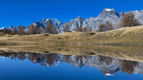 Majestic mountain landscape reflected in the calm lake under a clear sky, Pizzo Cornera 3083 m,