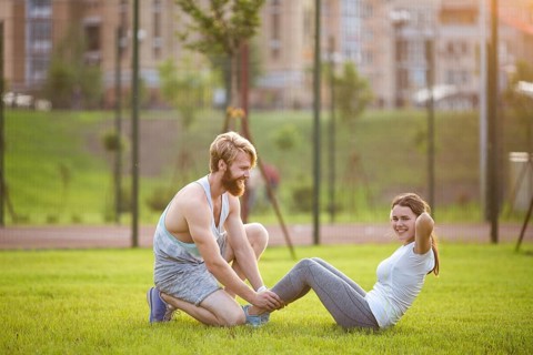 Sit ups fitness couple exercising sit up outside in graß Fit people working out cross training.