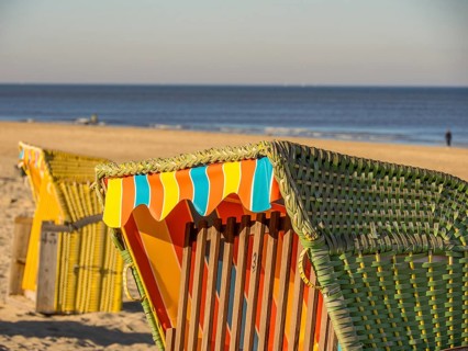 Close-up of a colourful beach chair on a sandy beach, overlooking the calm sea under a clear blue