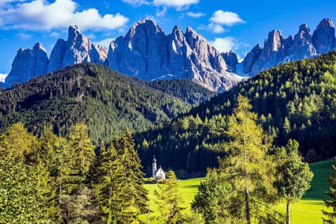 Dolomites, Tirol. Sunny warm autumn day. Rocky peaks and forested mountains surrounded by green