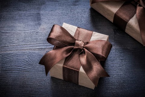 Present boxes with tied ribbons on wood board holiday concept