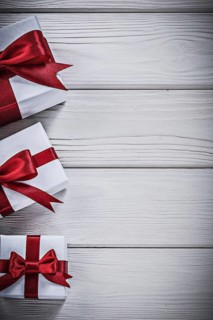 Present boxes with red bows on wooden board holidays concept