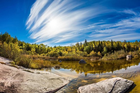 Indian summer in Manitoba, Canada. Incredible cirrus clouds over the Winnipeg River. Old Pinawa Dam