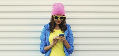 Happy smiling modern young woman with phone, teenage girl holding smartphone looking at device in