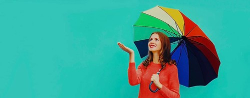 Autumn portrait of happy smiling young woman holding colorful umbrella wearing red knitted sweater