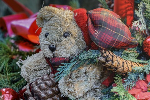 Close up of a Christmas decoration with red Christmas baubles, red candles, a green fir tree and a