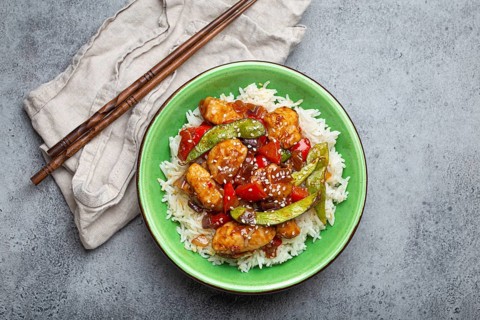 Asian sweet and sour sticky chicken with vegetables stir-fry and rice in ceramic bowl with
