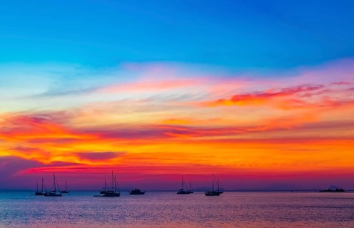 Yachts boats in front of the most beautiful colorful sunset at Tropical Paradise island Koh Phayam