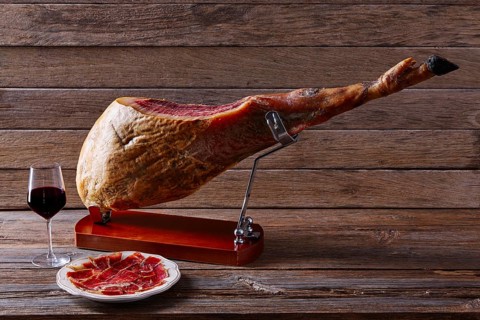 Iberian ham pata negra from Spain with red wine on wood background