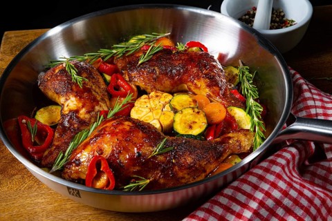 Roasted chicken legs with various vegetables and spices
