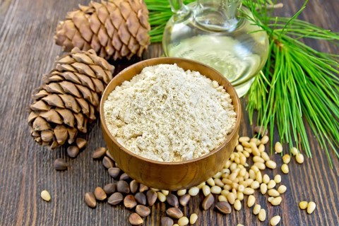 Flour cedar in a wooden bowl, cedar nuts and two cones, the oil in the glass carafe, cedar branch