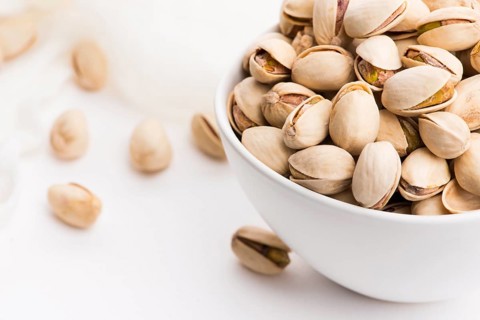 Bowl of roasted pistachios on a white background