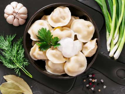 Traditional russian pelmeni, ravioli, dumplings with meat on black concrete background. Top view or