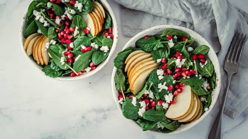Fresh salad with baby spinach, pear, pomegranate and cottage cheese. Two bowls with delicious