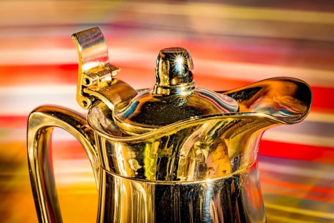 Shiny coffee pot against a colourful background
