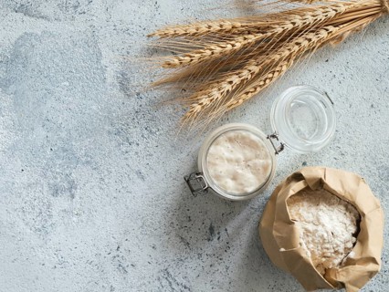 Wheat sourdough starter. Top view of bread making ingredients - glass jar with sourdough starter,