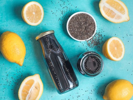 Detox activated charcoal black chia water or lemonade with lemon on bright blue background. Two