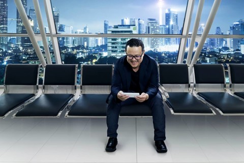 Young smiling businessman sitting at conference room and using smart phone