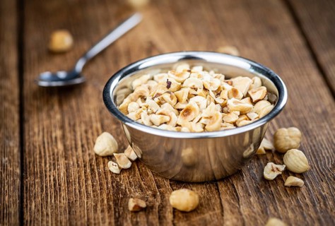 Portion of freshly chopped Hazelnuts on an old wooden table as detailed close up shot (selective