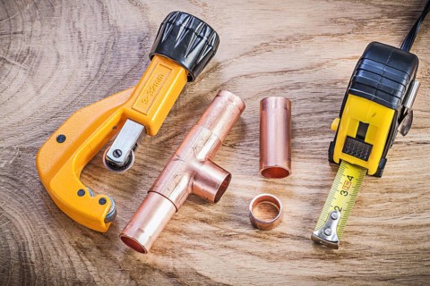 Copper water pipe cutter connectors tape measure on wood board plumbing brassware concept