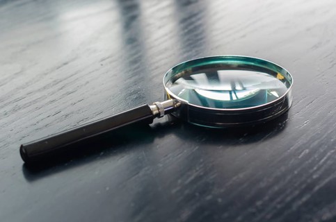 Magnifying glass on top of black wooden table top