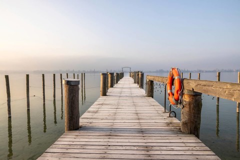 A jetty leads into a foggy lake, a lifebuoy hangs from a wooden railing, harbour, Allensbach,