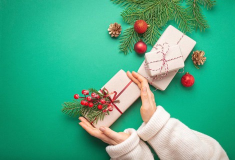 Christmas or New Year celebration green paper festive background with female hands holding wrapped