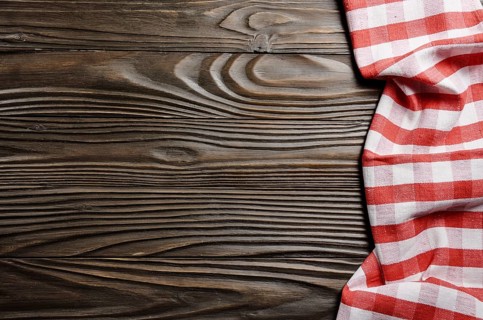 Red checkered napkin on brown wooden kitchen table with copy-space. Top view
