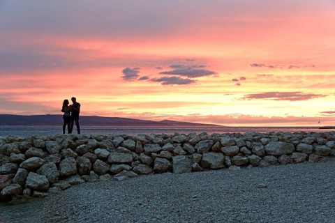 Sunset, couple on a pier, coast near Brela, behind them the island of Brac, Adriatic Sea,
