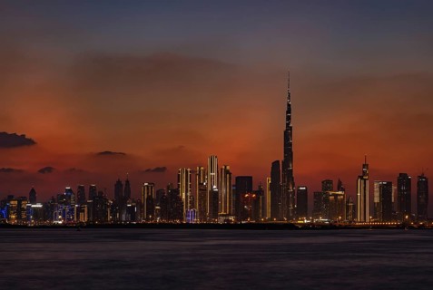 A colorful picture of Downtown Dubai at sunset, with the Burj Khalifa towering the other high rises