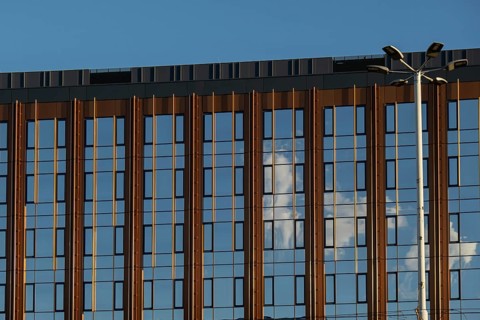 Modern office building exterior with glass facade on clear sky background. Transparent glass wall