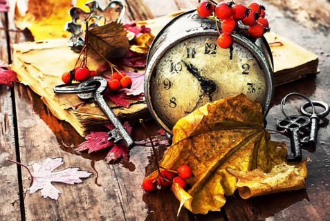 Od clock book and the keys on the wet table strewn with autumn leaves.Photo tinted
