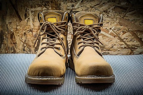 Two brown working boots on plywood background