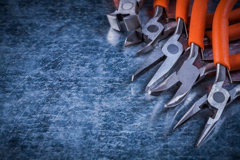 Insulated electric metal nippers gripping tongs on scratched metallic surface