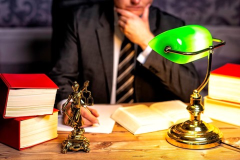 Office of a lawyer with books and a statue of Lady Justice, goddess Justitia, on the desk