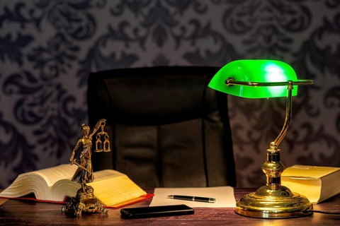 Office of a lawyer with books and a statue of Lady Justice, goddess Justitia, on the desk