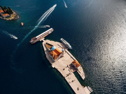 Boats moored near the island of Gospa od Skrpjela on the background of St. George island. Top view.