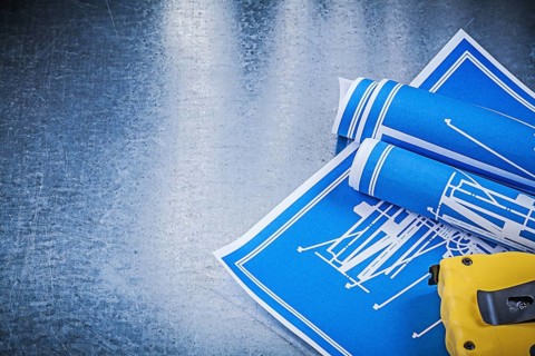 Composition of blue construction plans measuring tape on metallic background