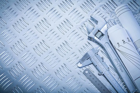 Engineering drawings vernier caliper monkey spanner on channeled metal background construction