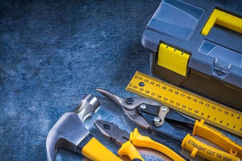 Scratched metallic background with toolbox hammer ruler pliers and tin snips construction concept