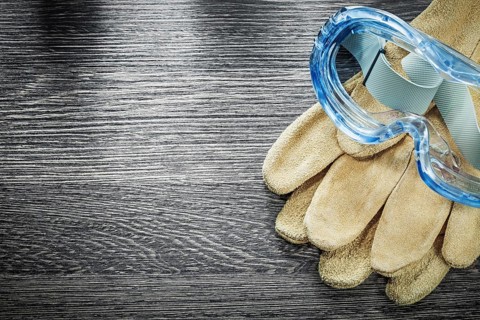 Protective gloves plastic goggles on wooden board