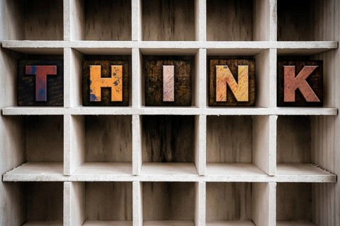 The word THINK written in vintage ink stained wooden letterpress type in a partitioned printer's