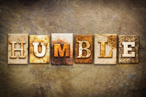 The word HUMBLE written in rusty metal letterpress type on an old aged leather background
